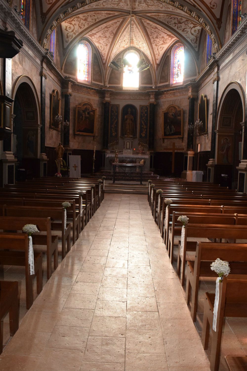 Mini bouquets de gypsophiles aux bouts de banc à l'église pour mariage religieux